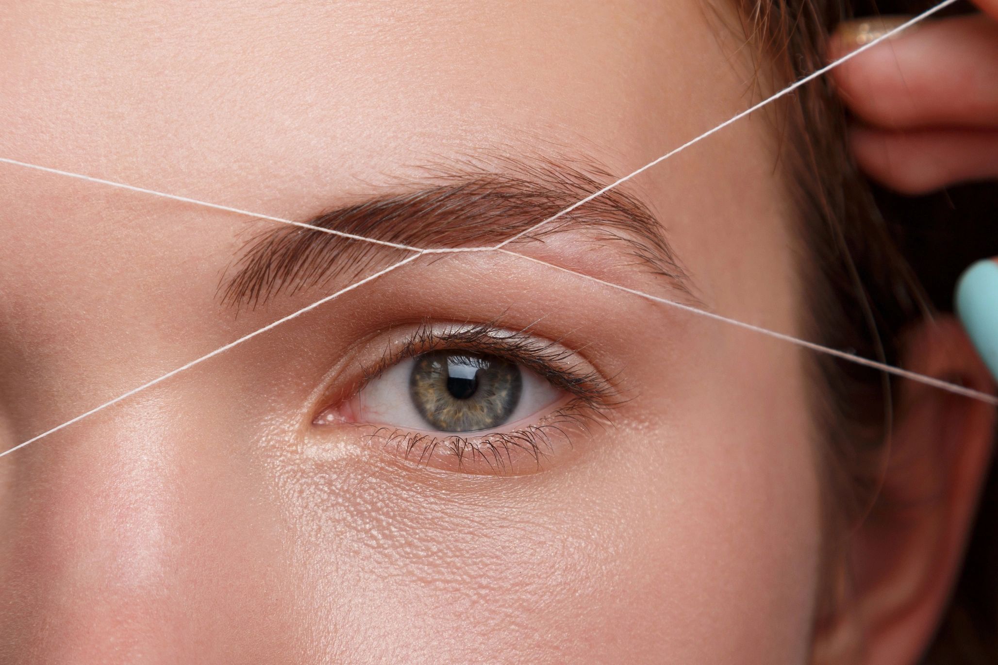 Close-up of eyebrow threading for precise hair removal.