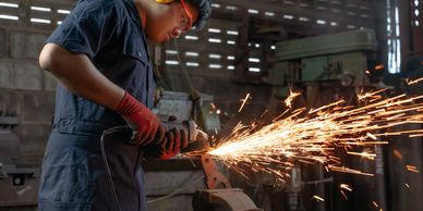 Worker using grinder producing sparks in a workshop.