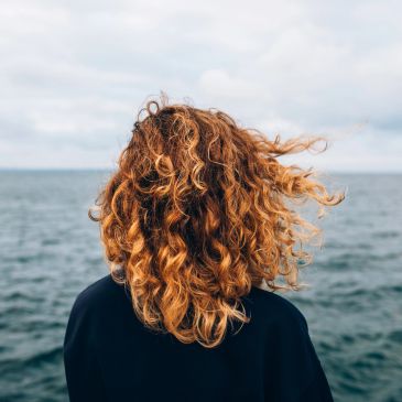 Curly hair blowing in the wind by the sea.