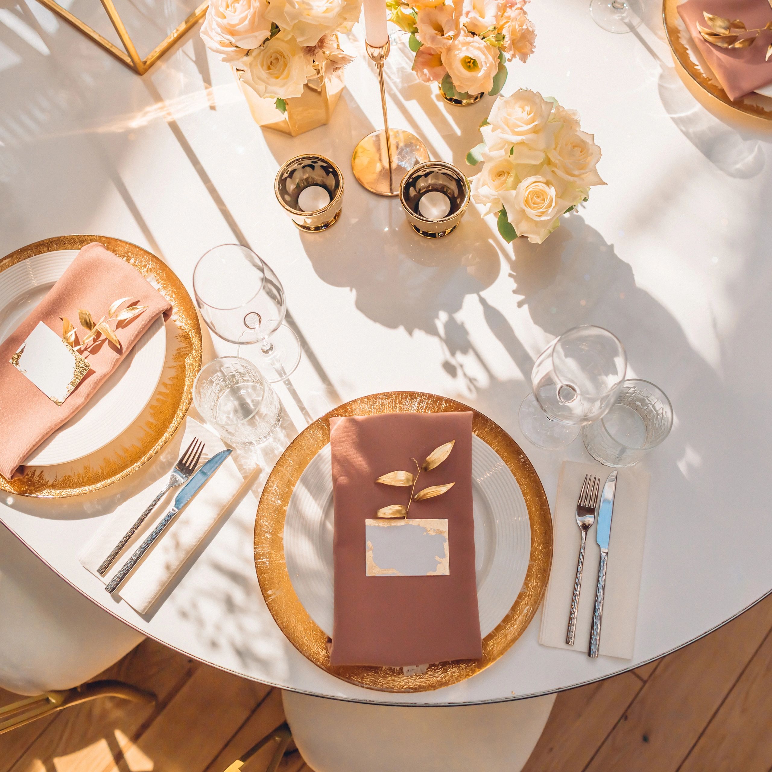 Elegant table setting with gold accents and soft pink napkins.