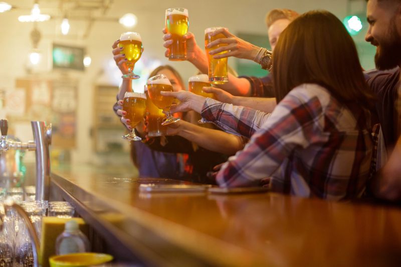 Group of people rising glasses in a toast for the New Year at the bar counter
