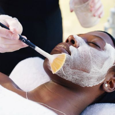 Woman receiving a facial mask treatment with a brush.
