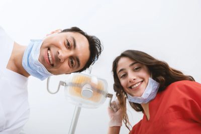 Dentist and assistant smiling with masks under chin.