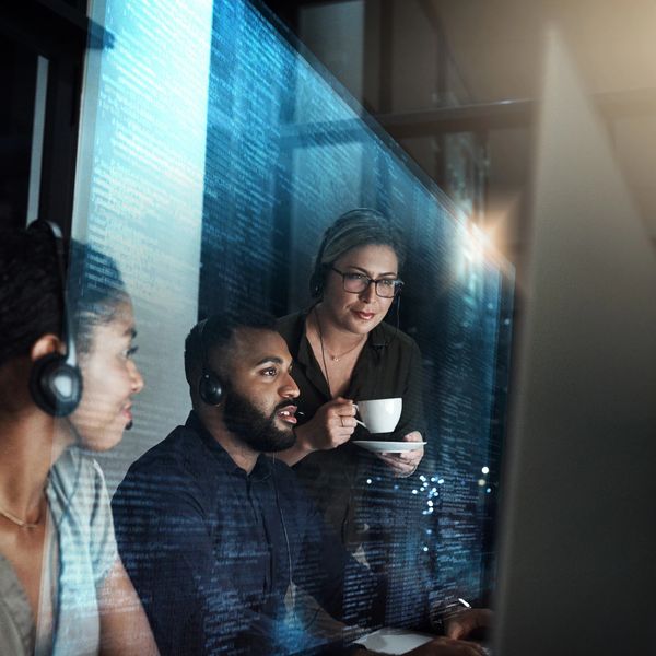 Team of tech professionals collaborating late at night with headsets on.