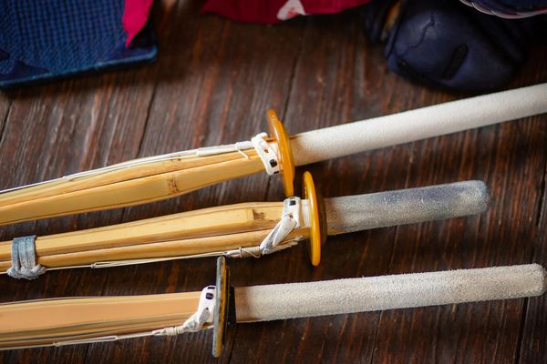 Three traditional Japanese bamboo practice swords on a wooden surface.
