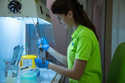 Scientist working with lab equipment in a controlled environment.
