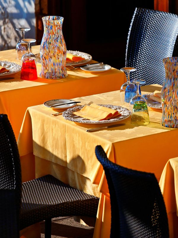 Elegant table setting with colorful glassware and yellow tablecloths.