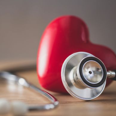 A stethoscope placed against a red heart model symbolizing heart health.