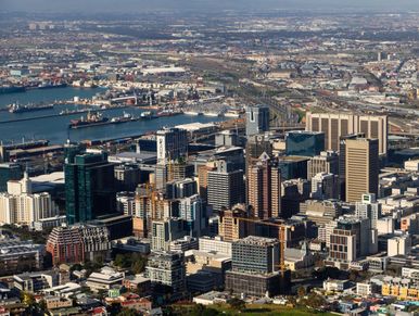 Aerial view of a bustling city with numerous skyscrapers and a busy harbor.