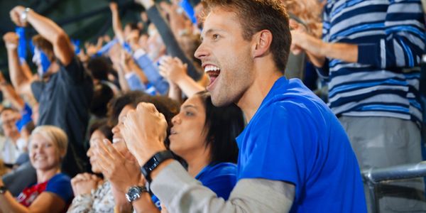 Excited sports fans cheering in the crowd.