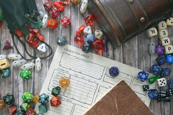 A tabletop RPG setup with a character sheet, dice, and a leather pouch.
