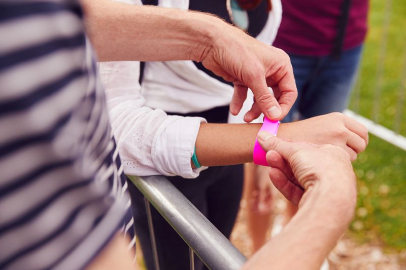 Close Up Of Friends At Entrance To Music Festival Putting On Security Wristbands
