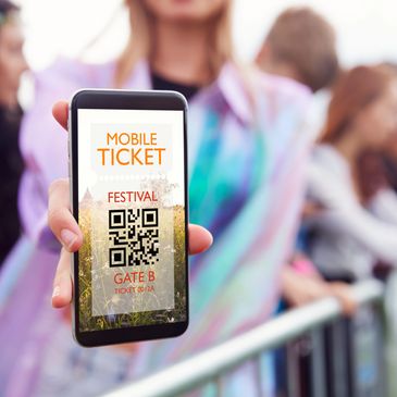 Person showing a mobile festival ticket with QR code at an event entrance.