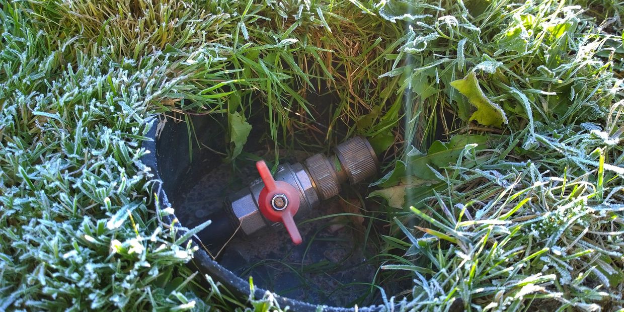 Frost-covered grass surrounding an irrigation valve.