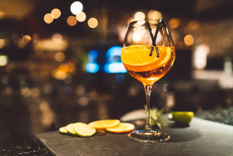 Garnished glass of Spritz cocktail in a bar. Garnished with lemon and lime slices.