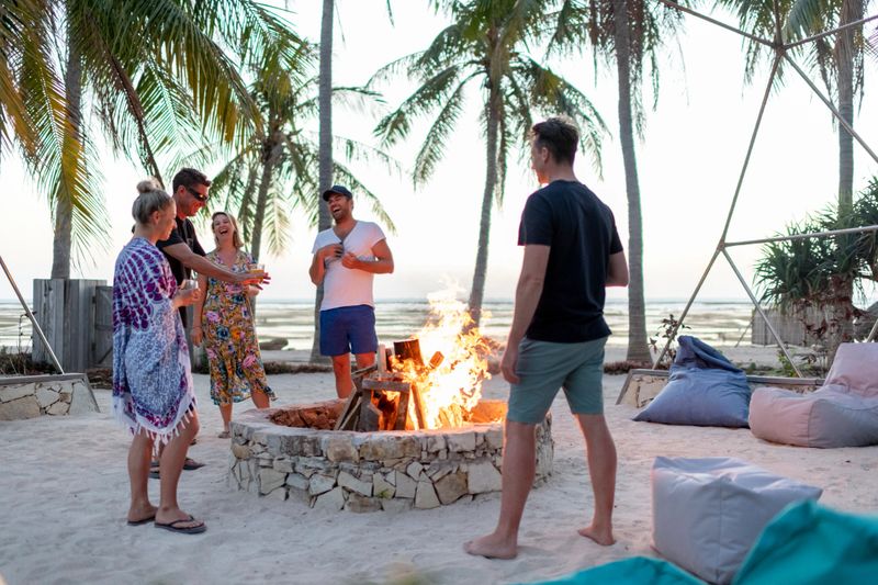 Friends laughing around the bonfire on the beach