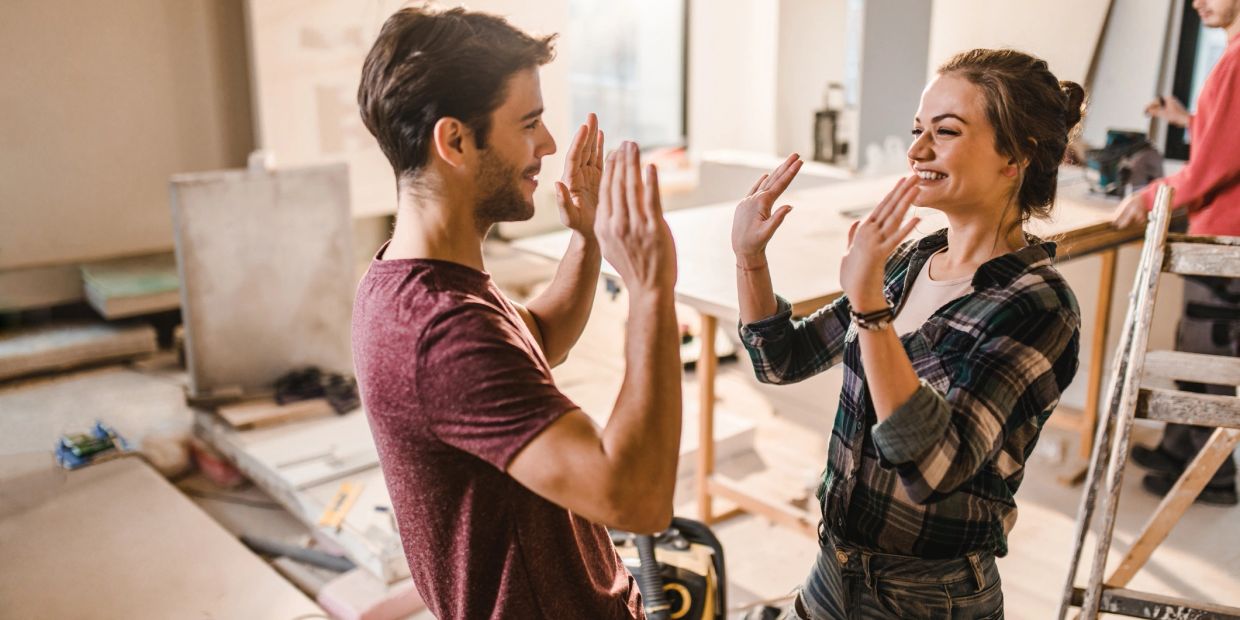 Two people happily giving each other a high-five in a workshop.