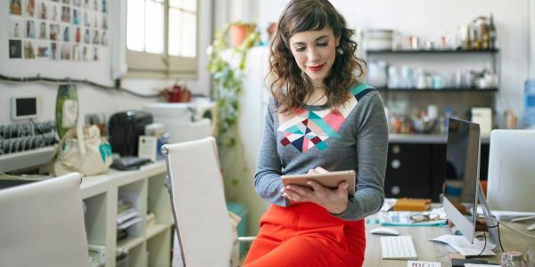 Woman in colorful sweater using tablet in office.