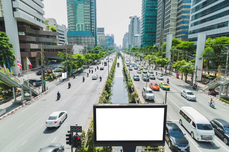 Blank billboard for outdoor advertising poster between the street at business district with office building and sky background.