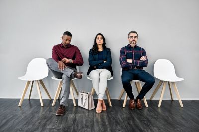 Five diverse professionals waiting against a dark wall.