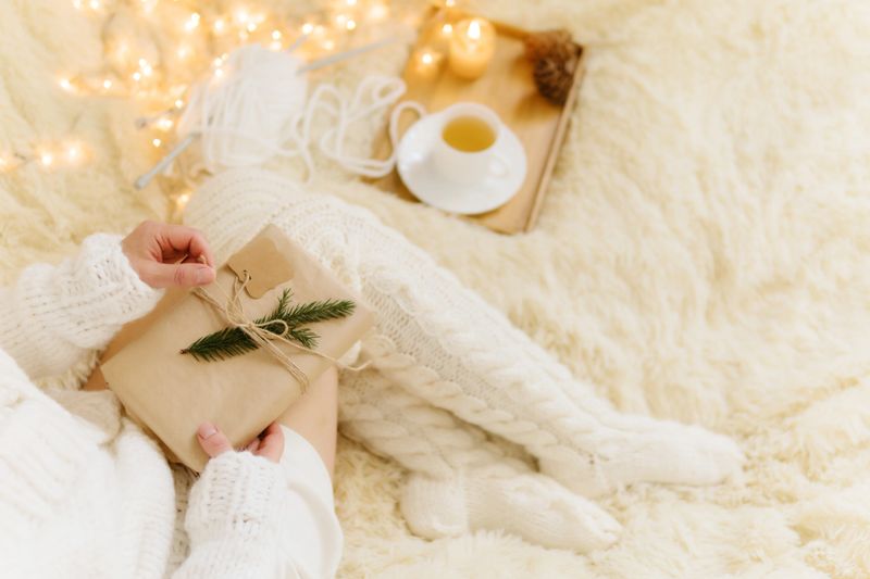 Woman holding gift in cozy room. Cold day in warm house. Concept Hygge. Merry Christmas!