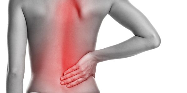 Person holding lower back with red area indicating pain or discomfort.