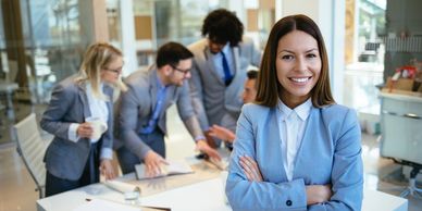Confident businesswoman with team working in background