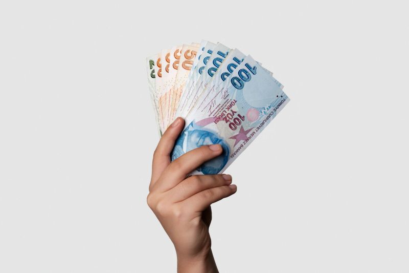 Unrecognizable person holding Turkish banknotes over gray background. Studio shot. Horizontal composition.
