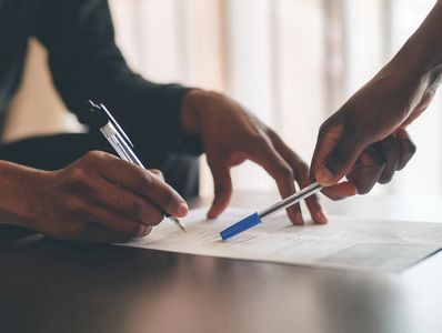 Two people collaborating on signing a document.