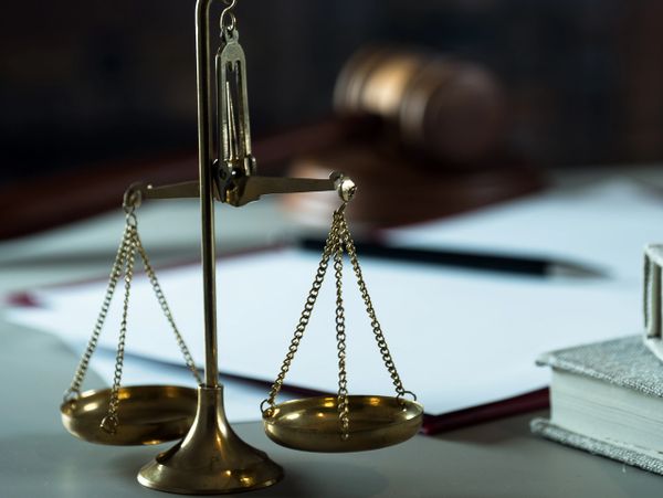 Golden scales of justice with a gavel and legal books in the background.