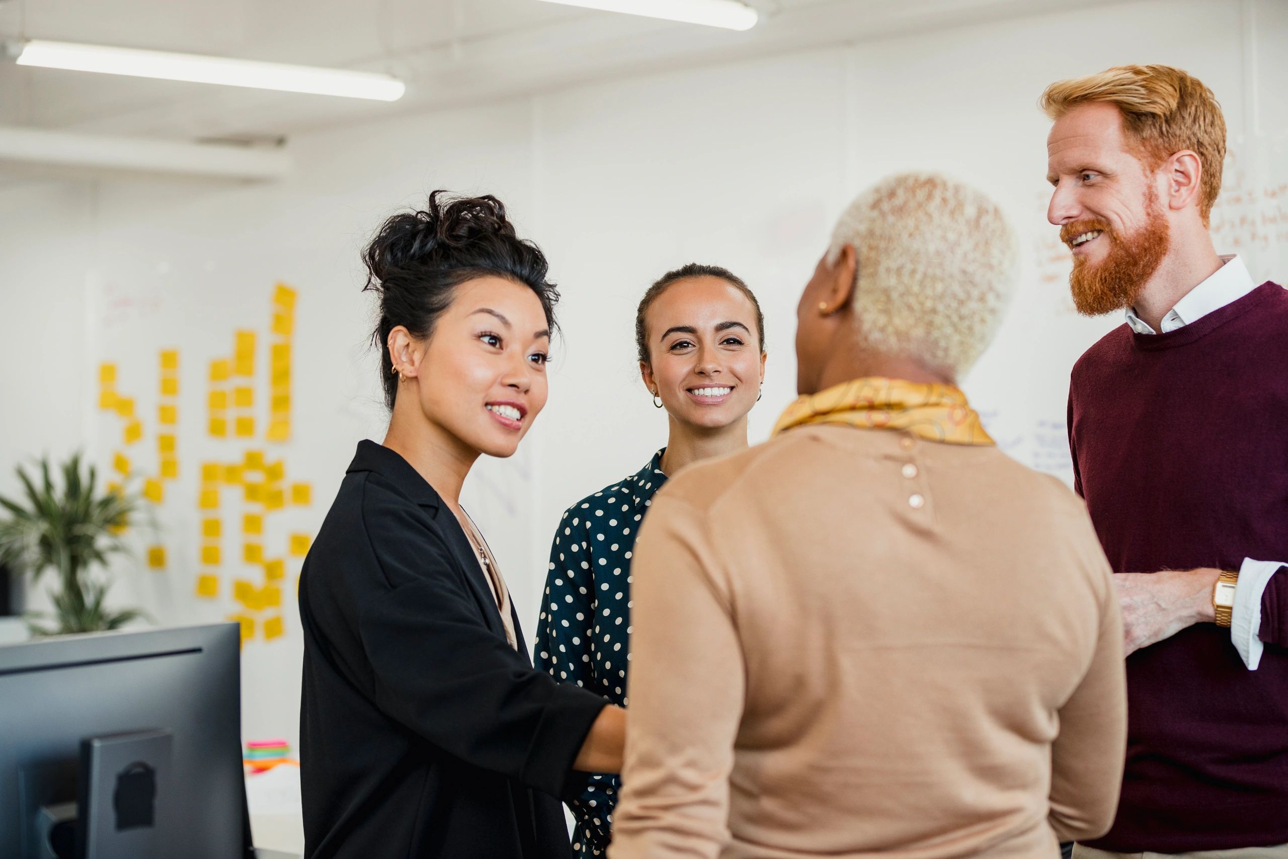 Four colleagues engaging in a friendly conversation in an office.