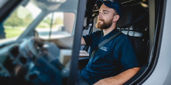 Delivery driver in uniform sitting in van, ready for work.