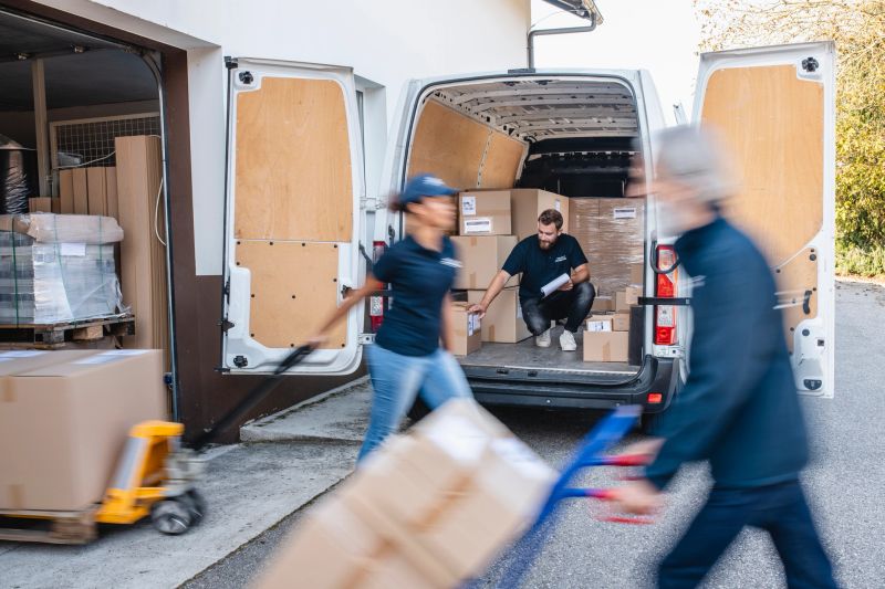 Blurred motion of expert independent gig delivery team moving parcels on hand truck and pallet jack for transport.