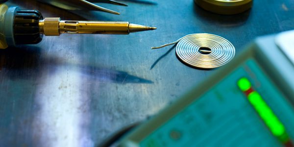 Soldering tools and wire on a workbench for electronics repair.