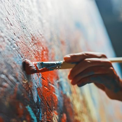 Hand painting with a brush on a colorful canvas.