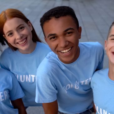 Happy volunteers smiling together in blue shirts.