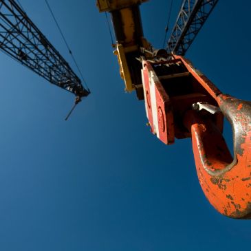 Close-up of a crane hook with a blue sky backdrop.