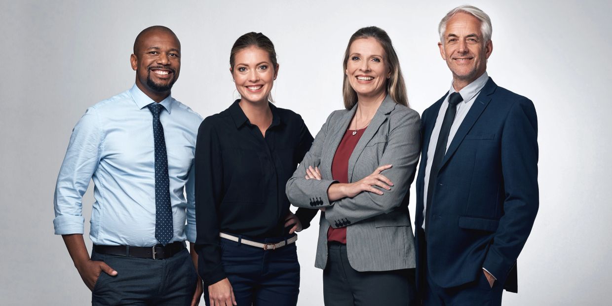 Four diverse professionals smiling confidently in business attire.