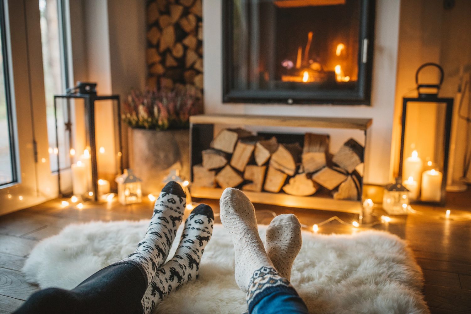 Two people relaxing by a cozy fireplace with warm socks and candlelight.