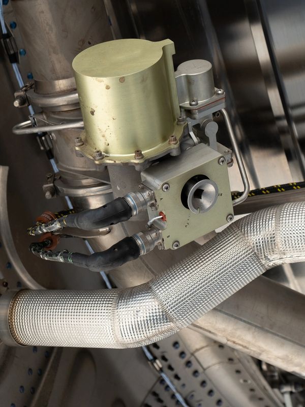 Close-up of metallic mechanical part with pipes and cables.