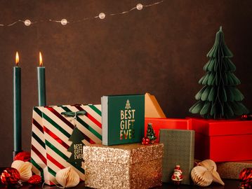 Festive Christmas gifts, candles, and decorations arranged on a table.
