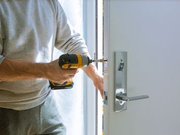 Person using a drill to install a door lock.
