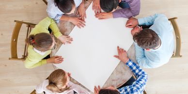 Group of six people sitting around a round table discussing.
