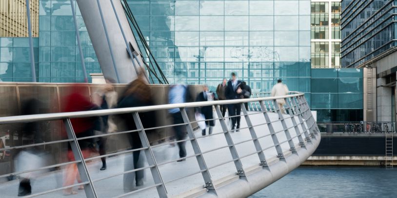 Blurred people walking on a modern bridge in an urban area.