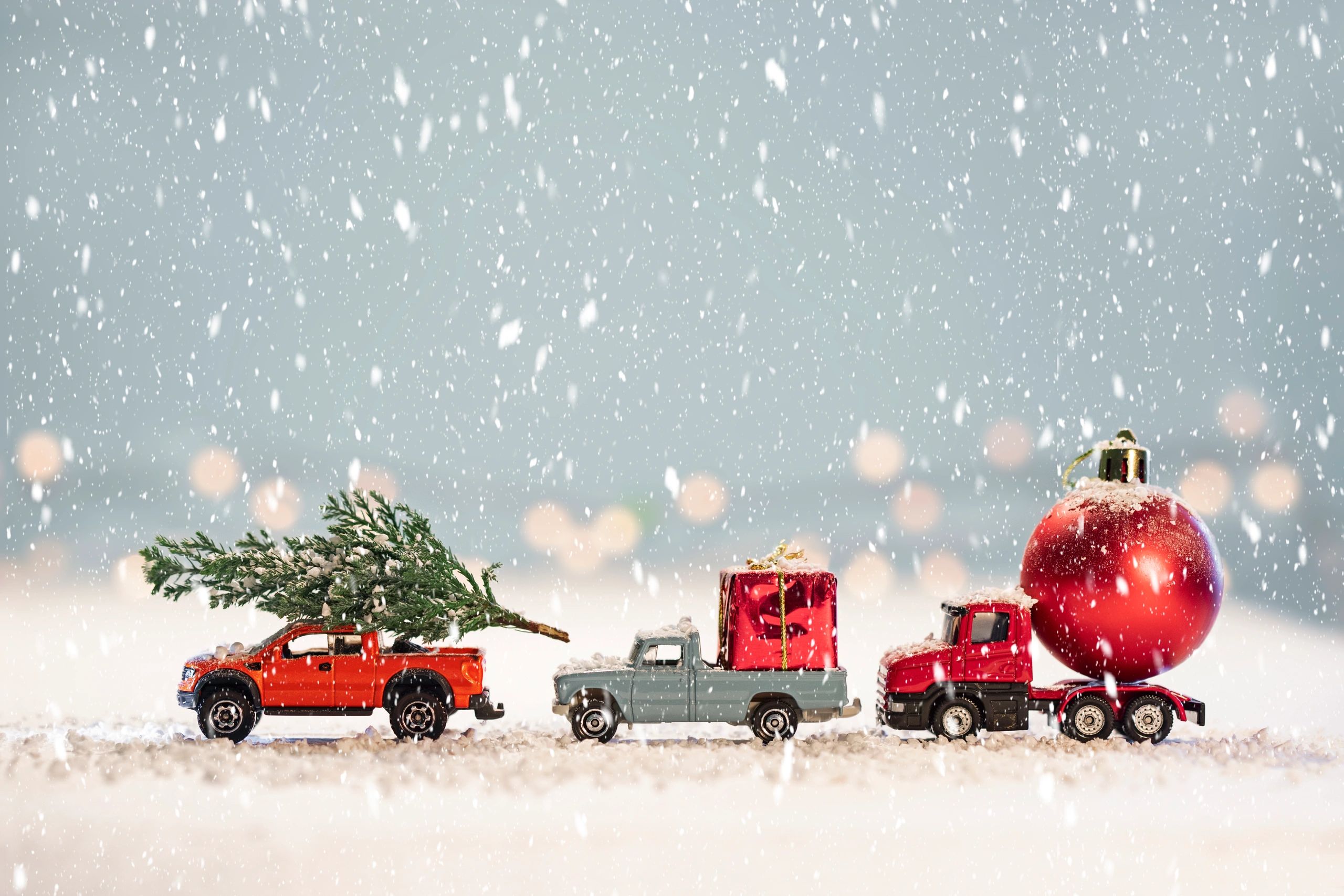 Christmas themed cars with a Christmas tree and a red bauble on a truck and a red Christmas present