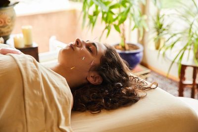 Woman receiving facial acupuncture treatment.