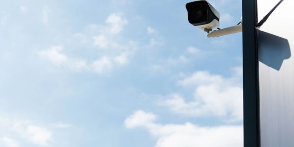 Security camera mounted on a post against a blue sky.