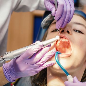 Dentist performing a dental procedure on a young patient with dental tools.