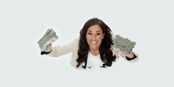 Smiling woman holding stacks of money against a white background.