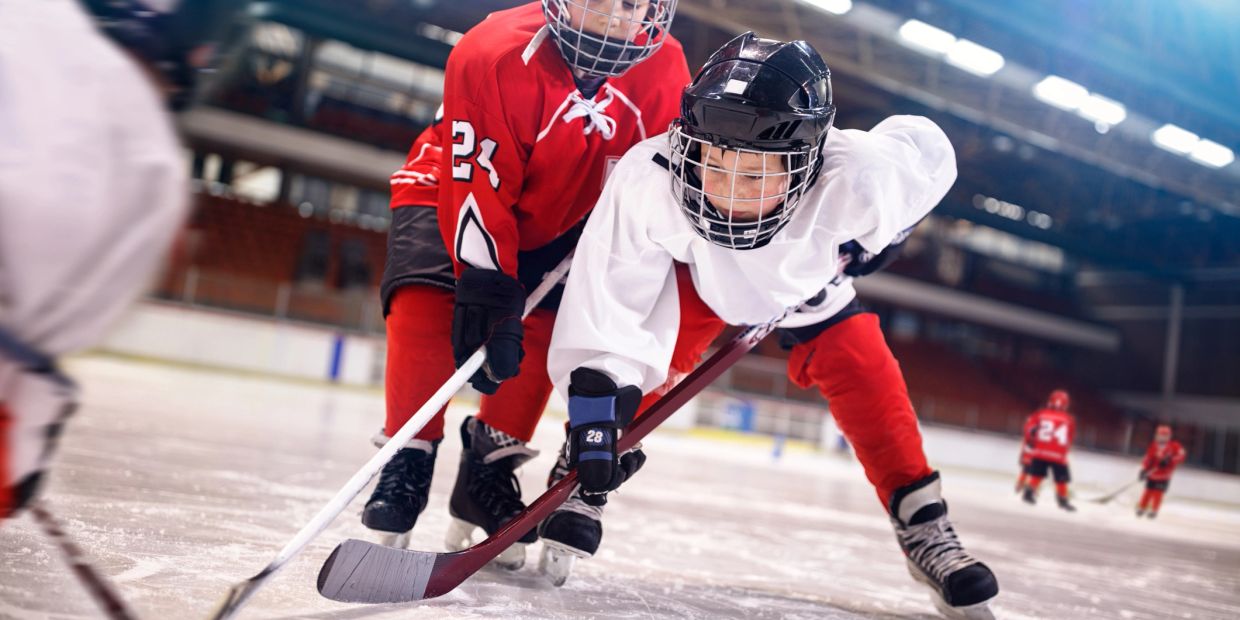 Two young hockey players competing for the puck on ice.